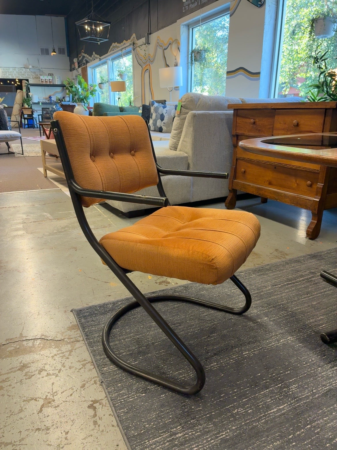 Orange upholstered cantilever accent chair with black metal frame