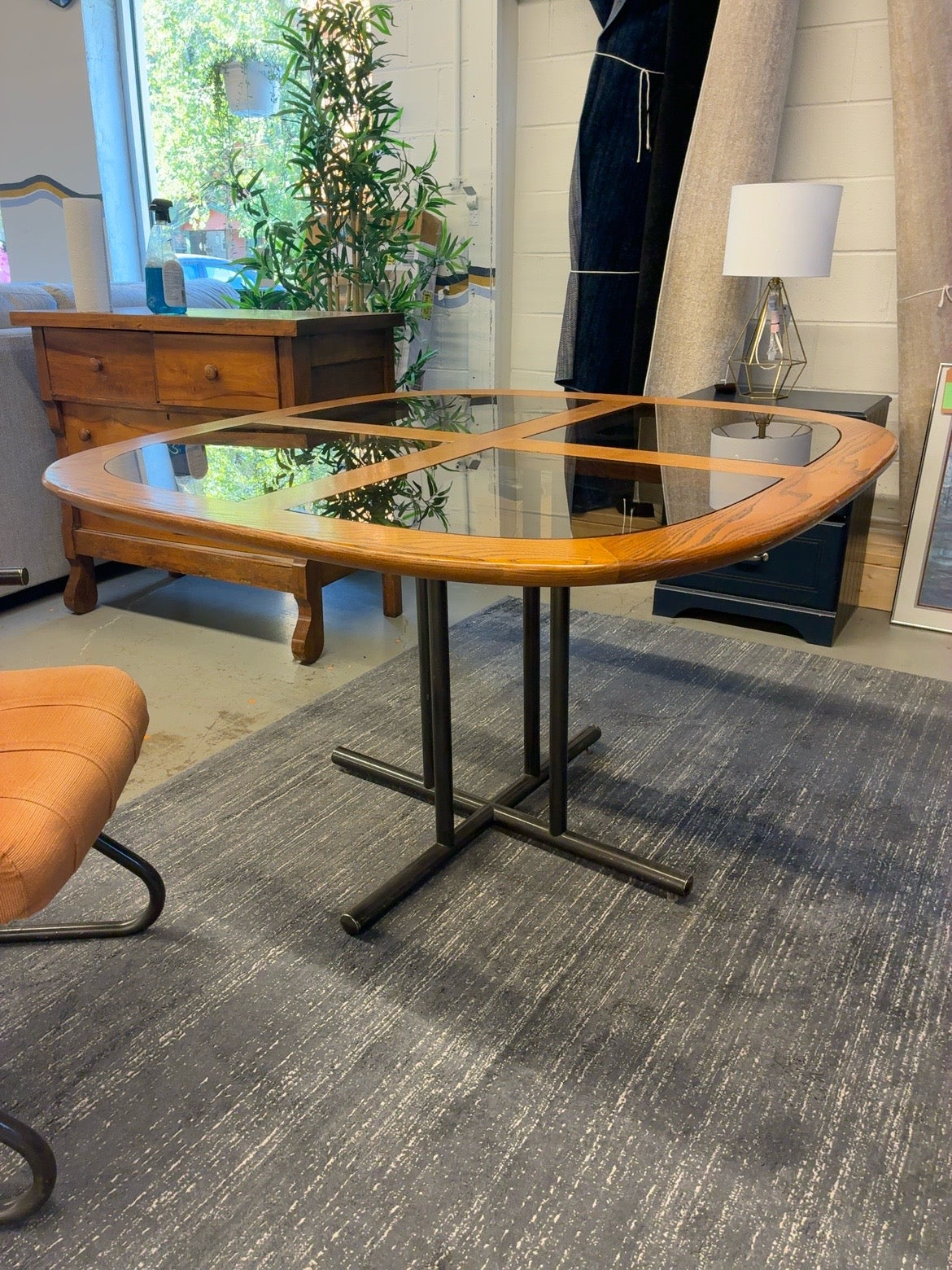 Wood-framed glass-top dining table with black metal pedestal base