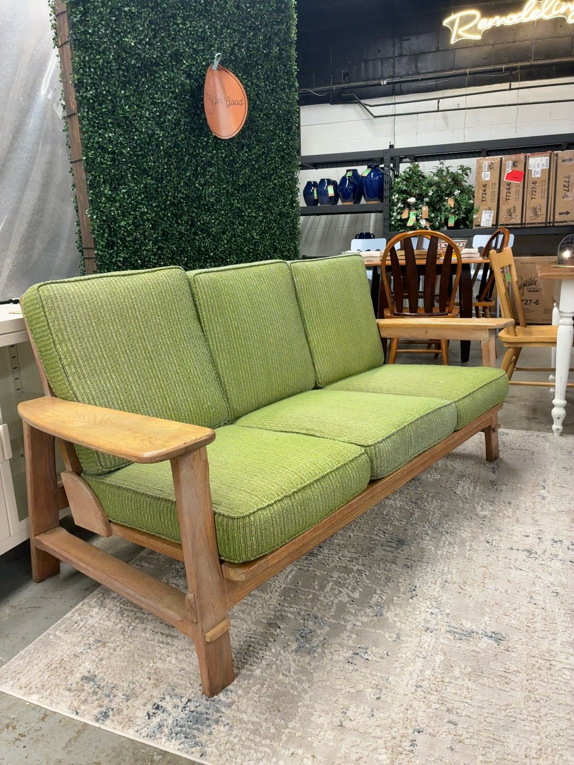 Green three-seat sofa with exposed wood frame