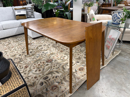 Walnut Astrid dining table with extension leaf beside it
