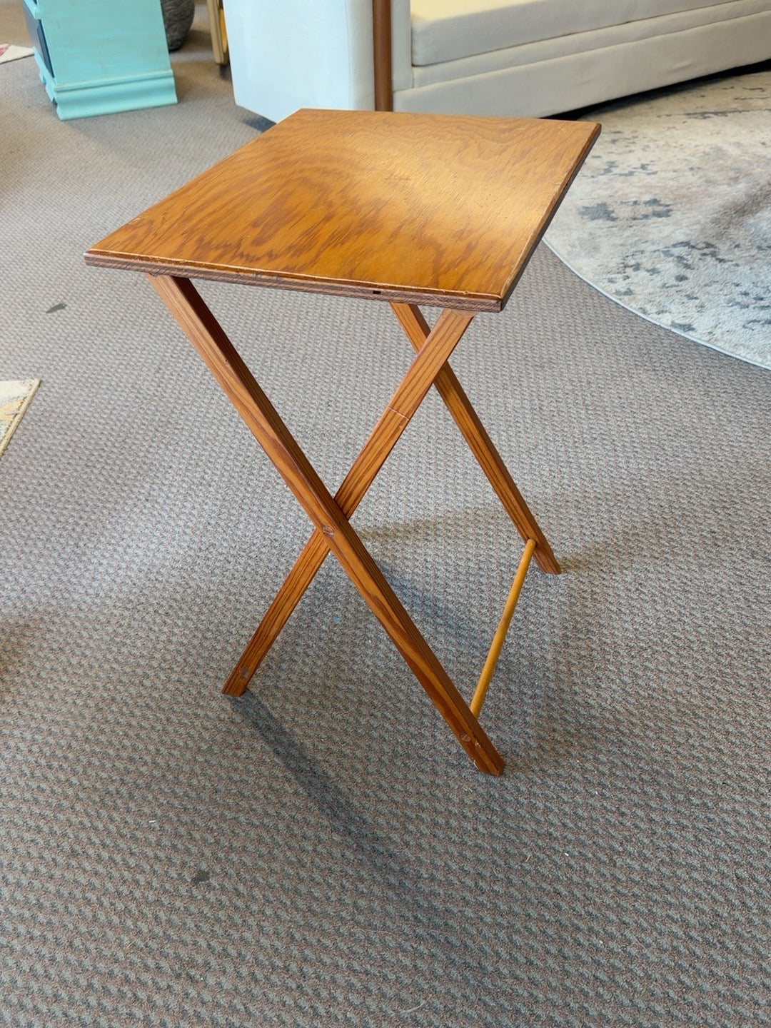 Honey brown folding TV tray table showing tabletop and crossed wooden legs