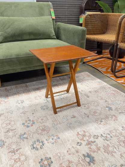 Honey brown wooden folding TV tray table with visible tabletop finish wear